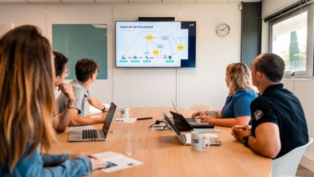 5 personnes regardent des écrans en réunion